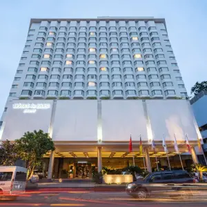 Tall hotel facade lit at dusk with cars and flags in front
