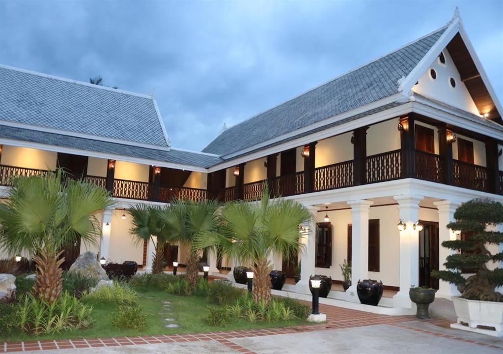 Houngvilai Hotel building with courtyard garden and palm trees at dusk