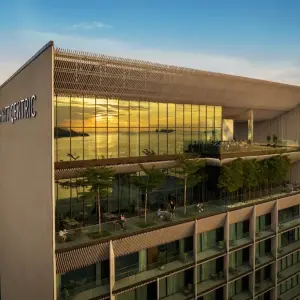 Hyatt Centric Kota Kinabalu hotel exterior with glass windows reflecting sunset and balconies with plants