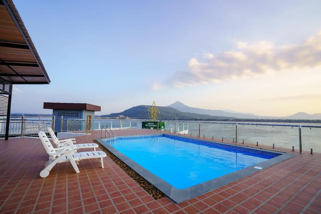 Rooftop pool and white loungers overlooking river and distant mountain at sunset