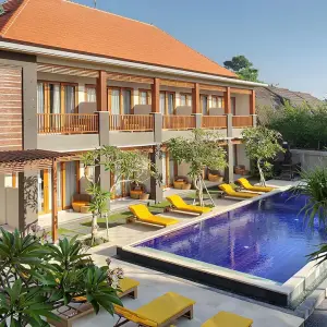 Hotel pool with yellow loungers and two-story building in sunny weather