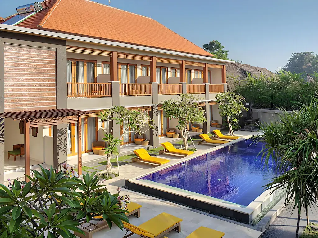 Hotel pool with yellow loungers and two-story building in sunny weather