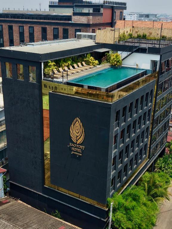 Lao Poet Hotel building with rooftop swimming pool and lounge chairs