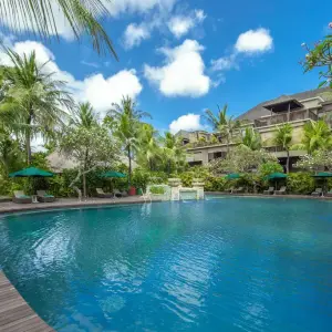 Resort swimming pool with palm trees and loungers under blue sky