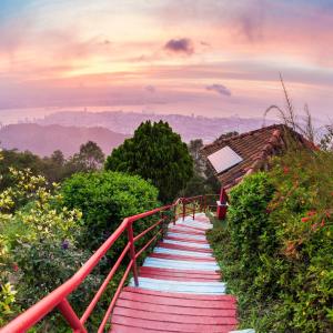 Red and white stairway descending hillside with cityscape at sunset