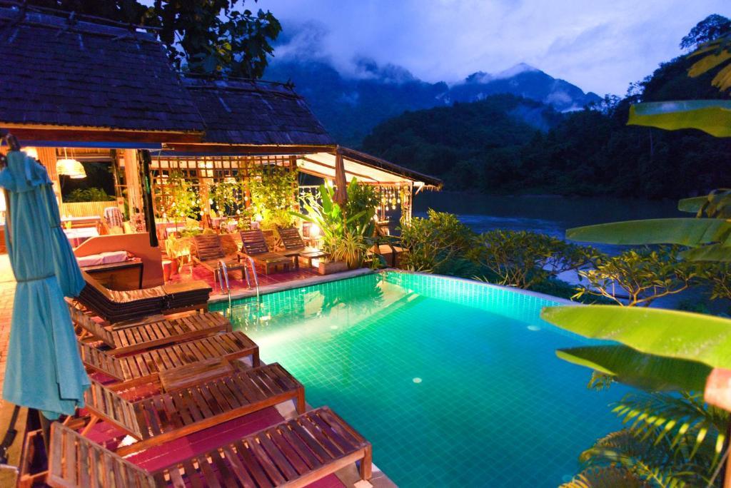 Evening outdoor pool with wooden loungers and mountain backdrop at Mandala Ou Resort