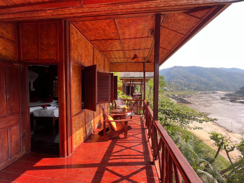 Wooden balcony at Mekong Riverside Lodge overlooking river and green mountains