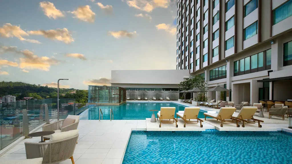 Rooftop pool area with lounge chairs and city view at sunset