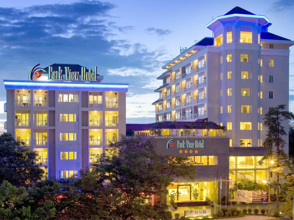 Park View Hotel building lit up at dusk with trees in the foreground