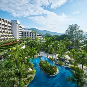 Pool area surrounded by palm trees and garden at Parkroyal Penang Resort under blue sky