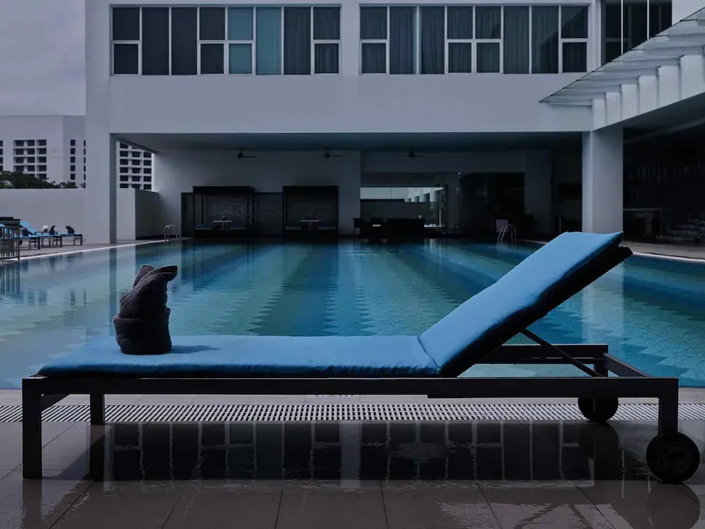 Blue pool lounger with towel sculpture beside calm hotel swimming pool