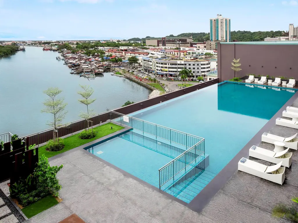 Rooftop infinity pool of Pullman Miri Waterfront hotel overlooking river and city buildings