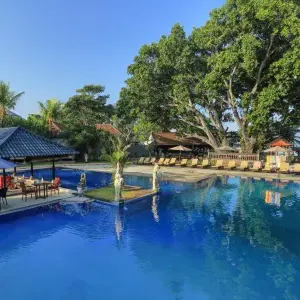 Outdoor swimming pool with lounge chairs and umbrellas at Puri Saron Seminyak resort.