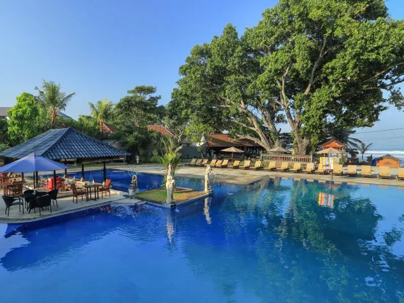 Outdoor swimming pool with lounge chairs and umbrellas at Puri Saron Seminyak resort.