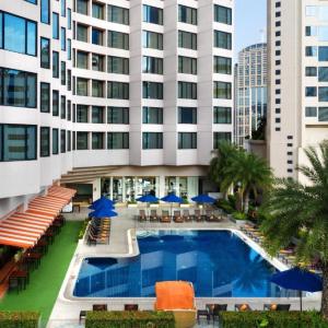 Outdoor swimming pool at Rembrandt Hotel Bangkok with chairs and blue umbrellas