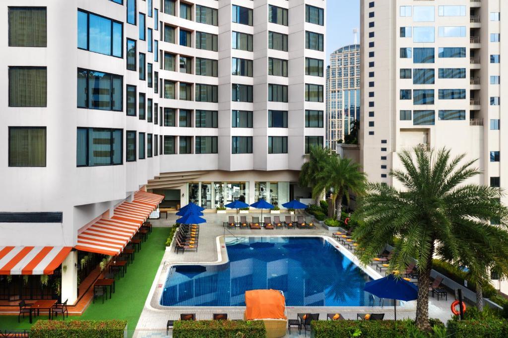 Outdoor swimming pool at Rembrandt Hotel Bangkok with chairs and blue umbrellas