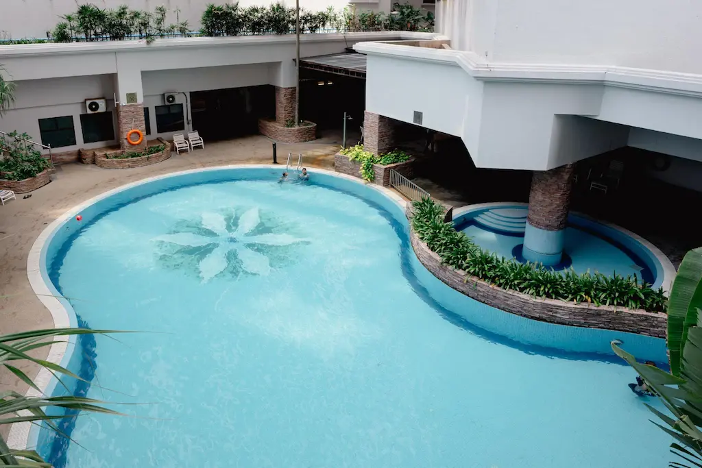 Curved hotel swimming pool with floral design and poolside seating