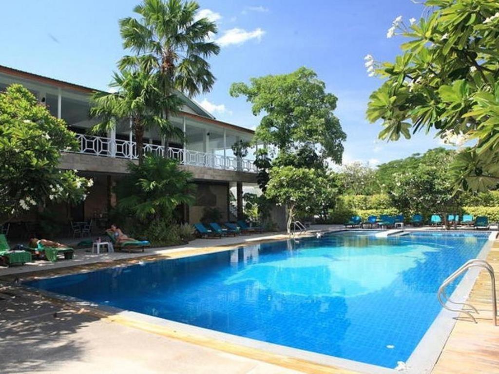Hotel outdoor swimming pool with lounge chairs and green trees