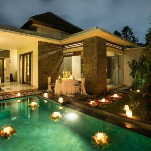 Villa patio at dusk with glowing pool, floating candles, and romantic dining table