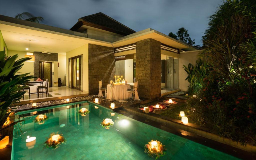 Villa patio at dusk with glowing pool, floating candles, and romantic dining table