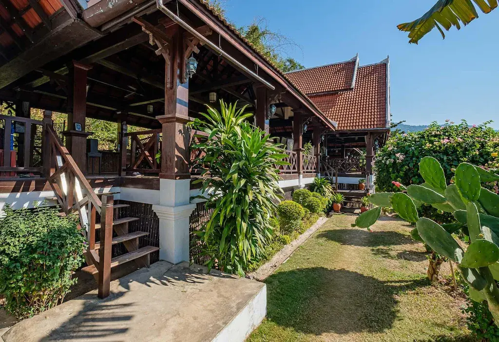 Wooden open-air terrace of Sanctuary Pakbeng Lodge with garden plants in daylight