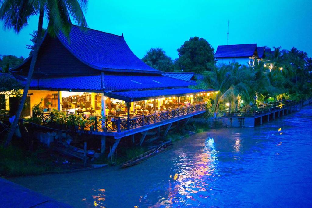 Night view of Sengahloune Resort riverside dining building with lights reflecting on water