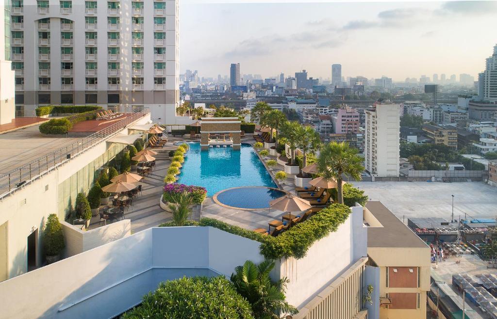 Rooftop pool with sun loungers and city skyline at The Berkeley Hotel Pratunam