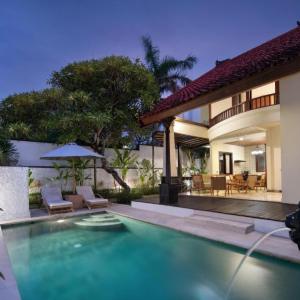Outdoor pool and dining area of a luxury villa at dusk with tropical greenery