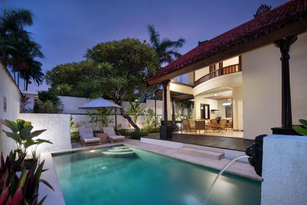 Outdoor pool and dining area of a luxury villa at dusk with tropical greenery