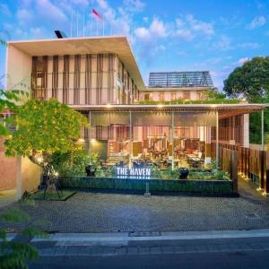 Exterior of modern hotel with open-air glass dining area and illuminated sign at dusk