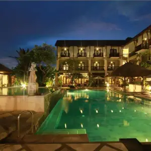 Lit swimming pool and resort balconies at night with tropical decor
