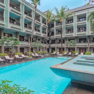 Outdoor swimming pool with lounge chairs and palm trees at The Vira Bali resort courtyard