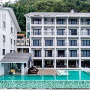 Modern white hotel with balconies and rooftop infinity pool by forest hillside