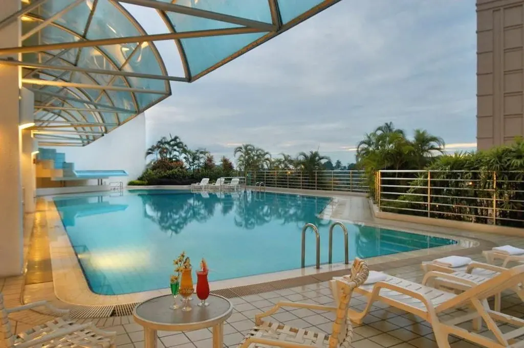 Outdoor hotel swimming pool with lounge chairs and drinks on table