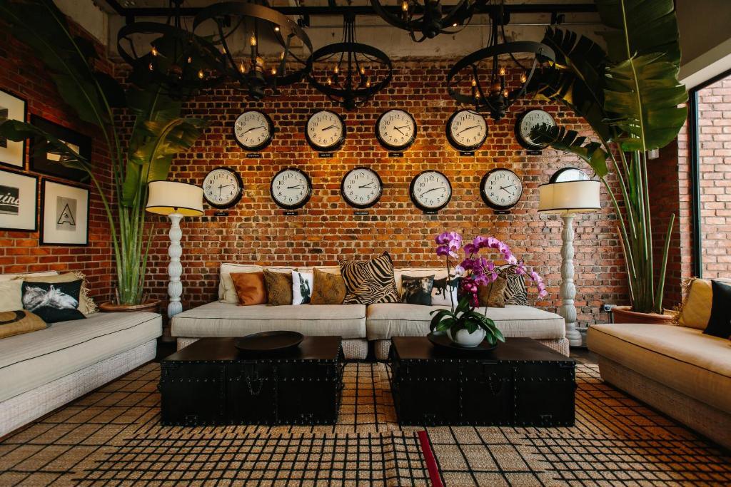 Lounge with brick wall, many clocks, sofas, plants, and coffee tables
