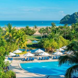 Resort pool with umbrellas overlooking tropical beach and ocean