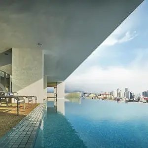 Rooftop infinity pool and loungers overlooking city skyline under partly cloudy sky