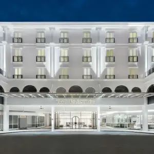 White illuminated hotel façade with balconies and main entrance at night