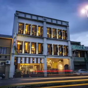 Street view of The Ranee Boutique Suites hotel lit up at dusk with vehicle light trails
