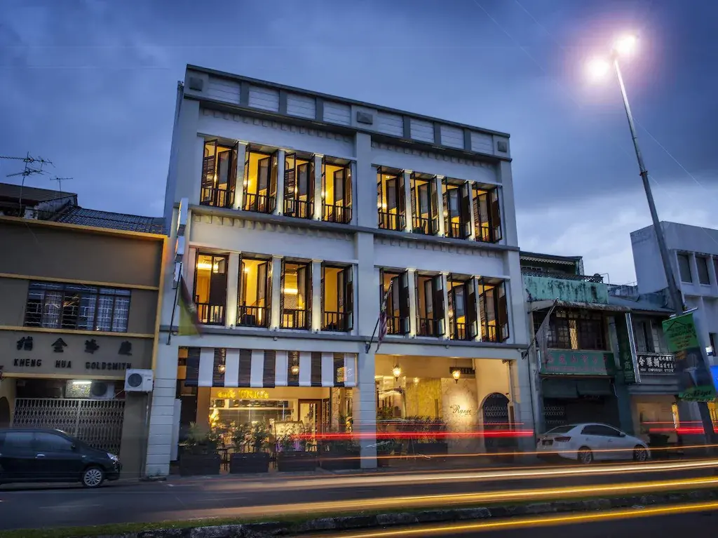 Street view of The Ranee Boutique Suites hotel lit up at dusk with vehicle light trails