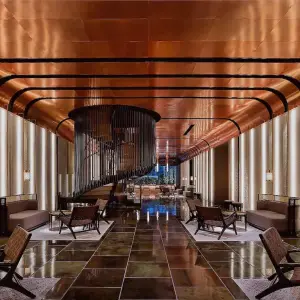 Hotel lobby with bronze ceiling, spiral staircase, and modern seating