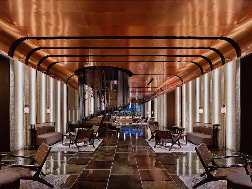Hotel lobby with bronze ceiling, spiral staircase, and modern seating